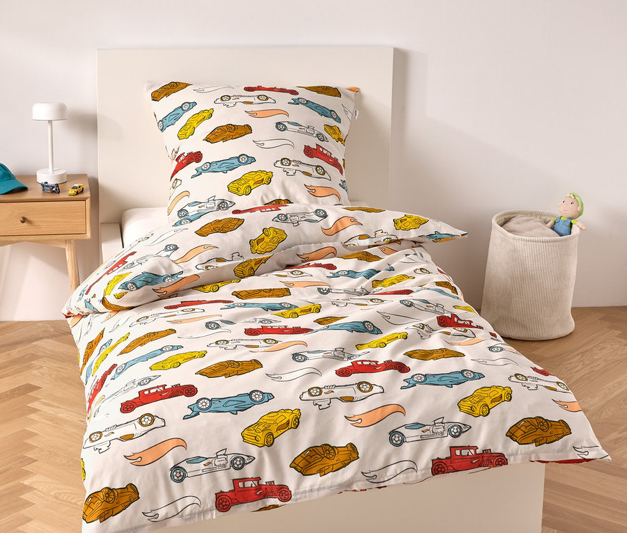 Bett mit weißem Rahmen und Bettwäsche mit Autoaufdruck.