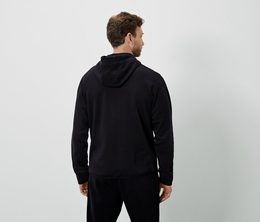 Mann von hinten trägt einen schwarzen Kapuzenpullover und eine schwarze Trainingshose.