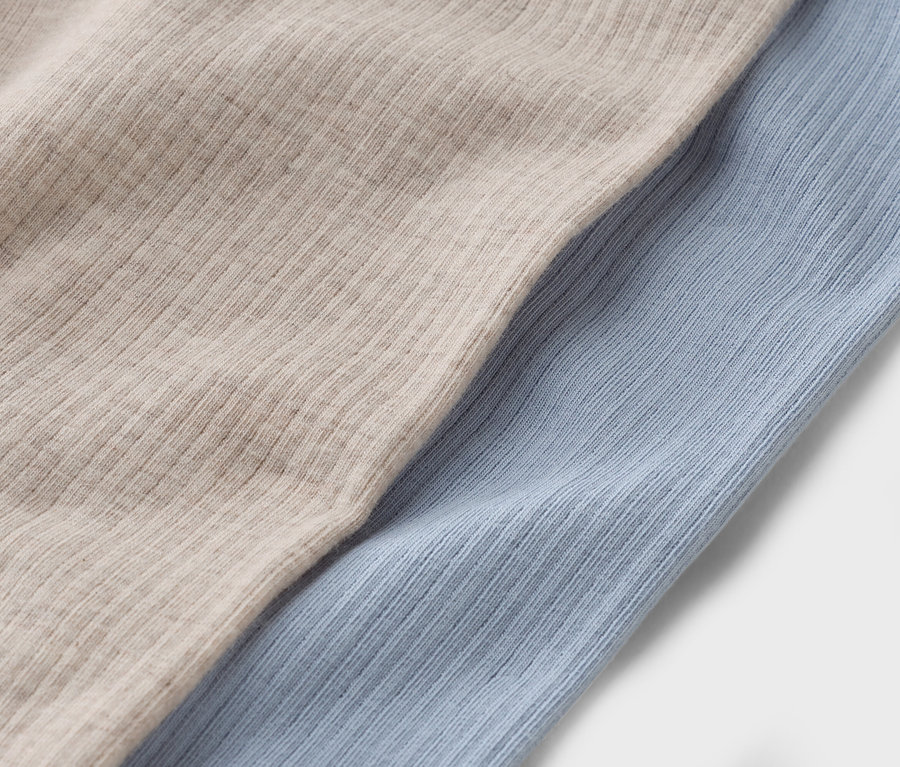 Nahaufnahme von zwei Stoffstücken: einem beigen und einem hellblauen.