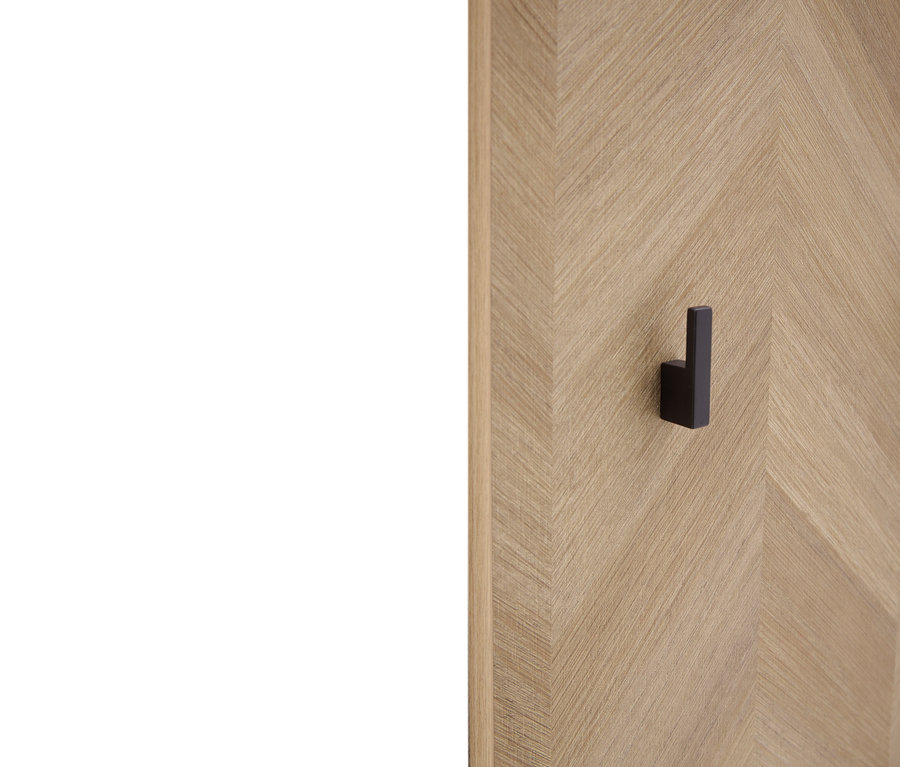 Schwarzer Wandhaken an einer Holzwand mit Fischgrätenmuster.