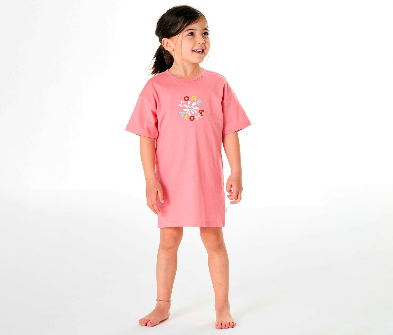 Mädchen trägt ein rosafarbenes SCHIESSER Kinder-Nachthemd mit einem bunten Aufdruck.
