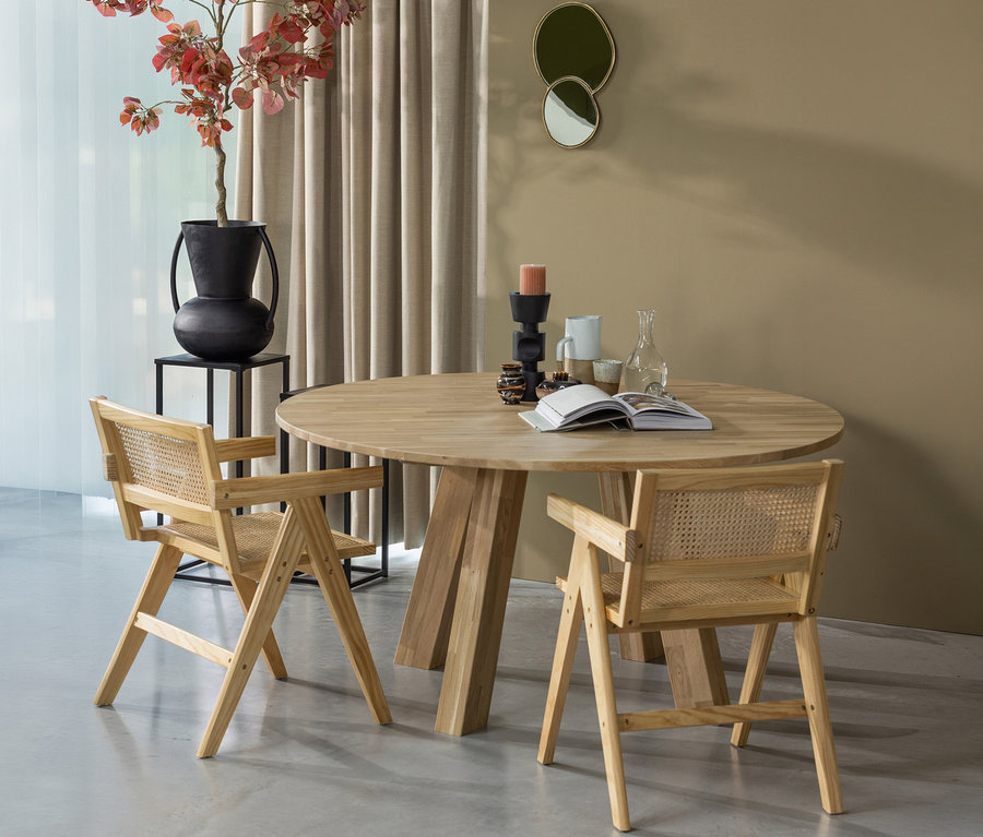 Zwei Holzstühle stehen am runden WOOOD »Rhonda« Esstisch (ca. 150 cm). Auf dem Tisch liegen ein Buch, Kerzen und Gläser.