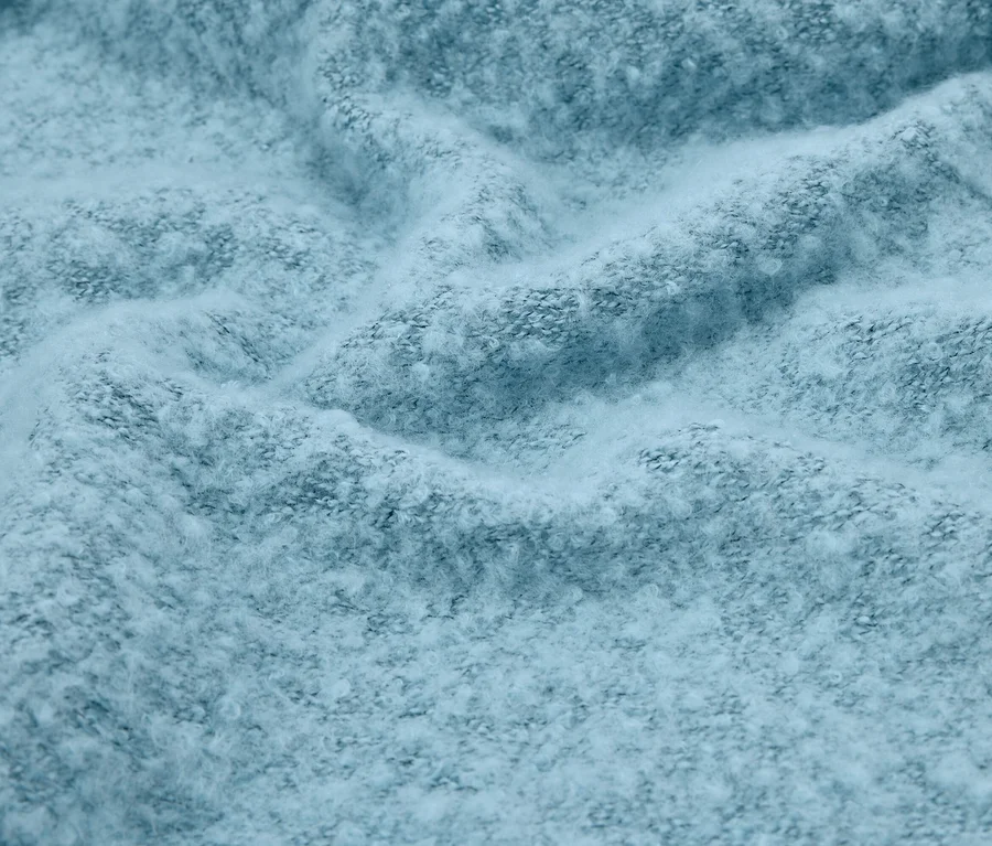 Nahaufnahme eines gefalteten, hellblauen Stoffes mit flauschiger Textur.