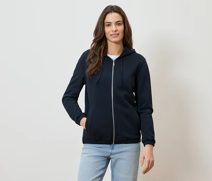 Frau mit marineblauer Kapuzenjacke mit Reißverschluss und Jeans.