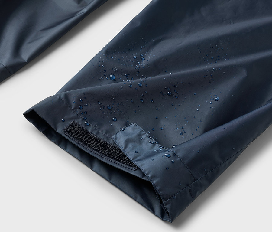 Nahaufnahme von wasserabweisenden, marineblauen Ärmeln mit Klettverschluss und Wassertropfen darauf.