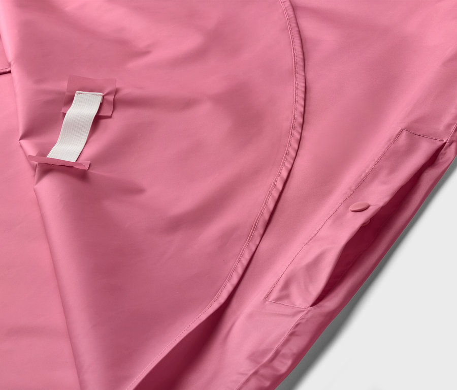 Nahaufnahme einer rosafarbenen Jacke mit einer weißen Schlaufe und einer Tasche mit Knopf.