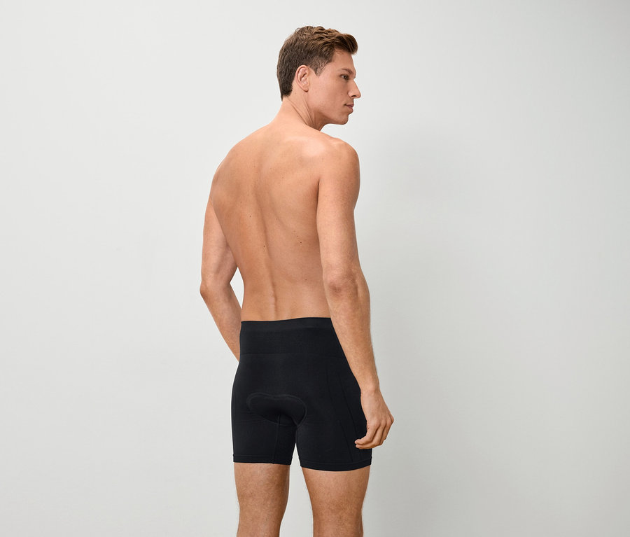 Rückansicht eines Mannes mit nacktem Oberkörper, der schwarze Boxershorts trägt.