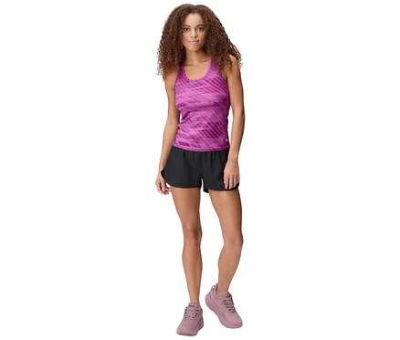 Frau steht in pinkem gemustertem Tanktop, schwarzen FILA Damen-Funktionsshorts und pinken Turnschuhen.