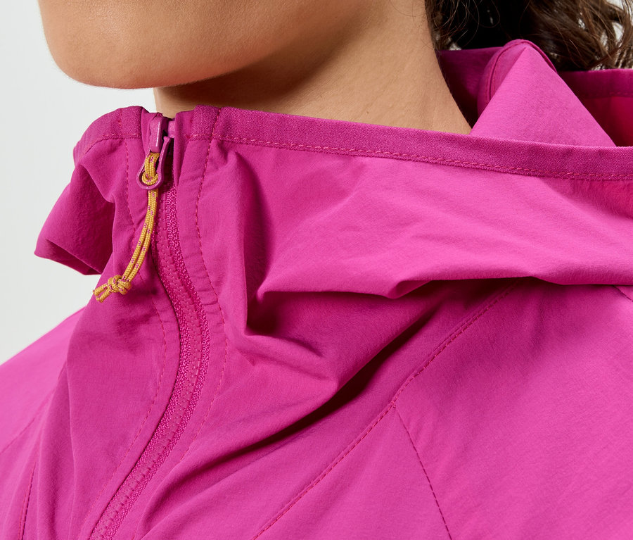 Nahaufnahme einer Frau, die eine pinke Jacke mit Kapuze und gelbem Reißverschluss trägt.