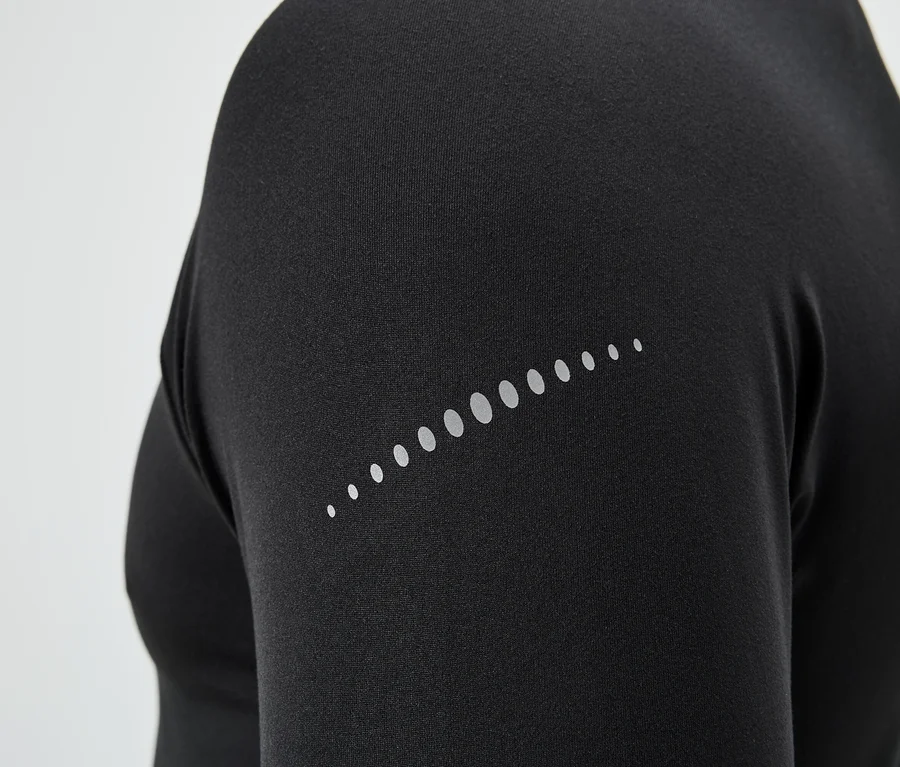 Schwarzes Oberteil mit reflektierenden Punkten auf dem Ärmel.