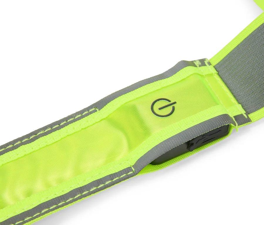 Nahaufnahme eines neongelben Reflexbandes mit grauen Reflexstreifen, einem Einschaltsymbol und einer dunklen Steuereinheit.