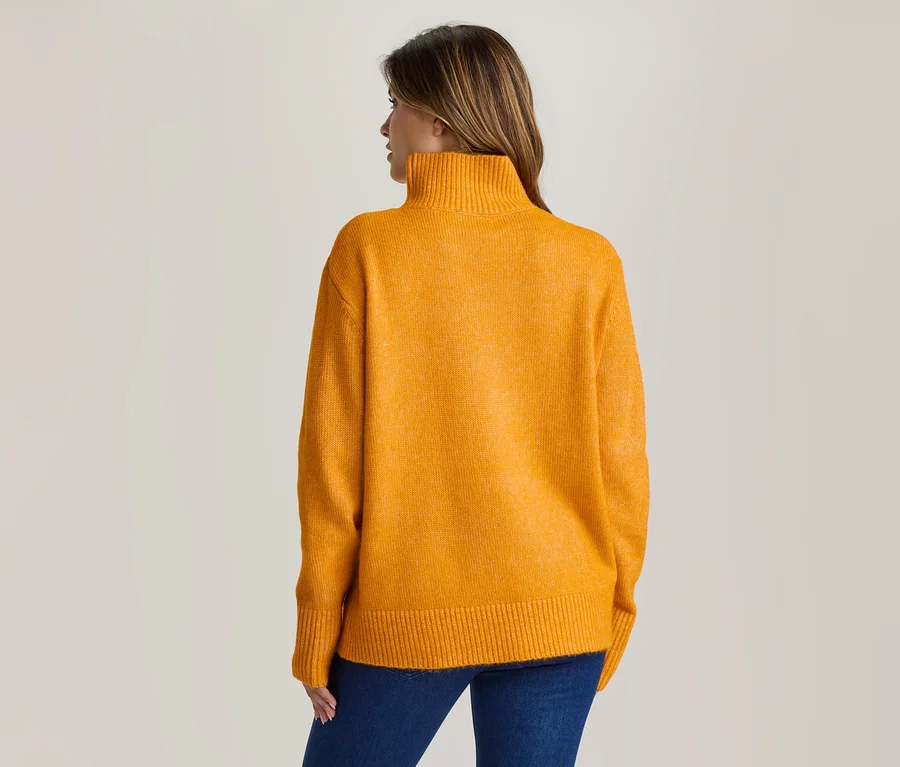Frau von hinten, trägt einen gelben Rollkragenpullover und blaue Jeans.