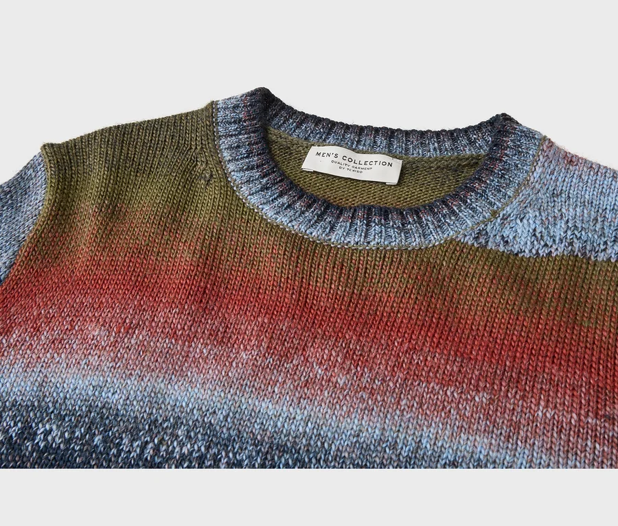 Gestrickter Herren-Ombré-Pullover, Farbverlauf von Olivgrün über Rot zu Hell- und Dunkelblau. Etikett "MEN'S COLLECTION by TCHIBO" am Kragen.
