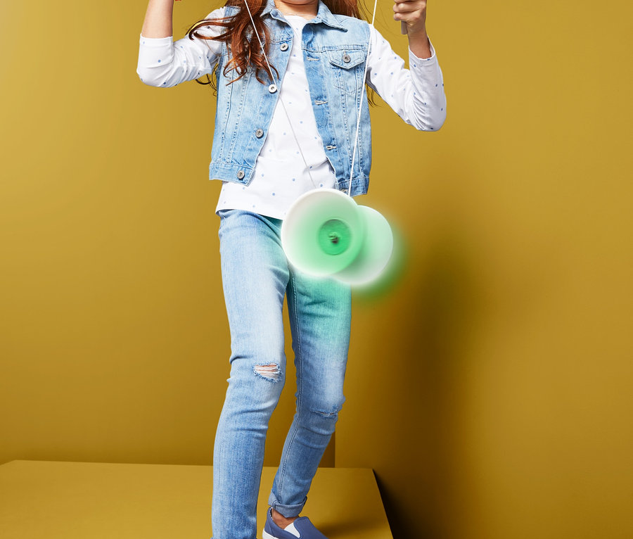 Ein Mädchen steht und spielt mit einem Diabolo »Glow in the dark«.