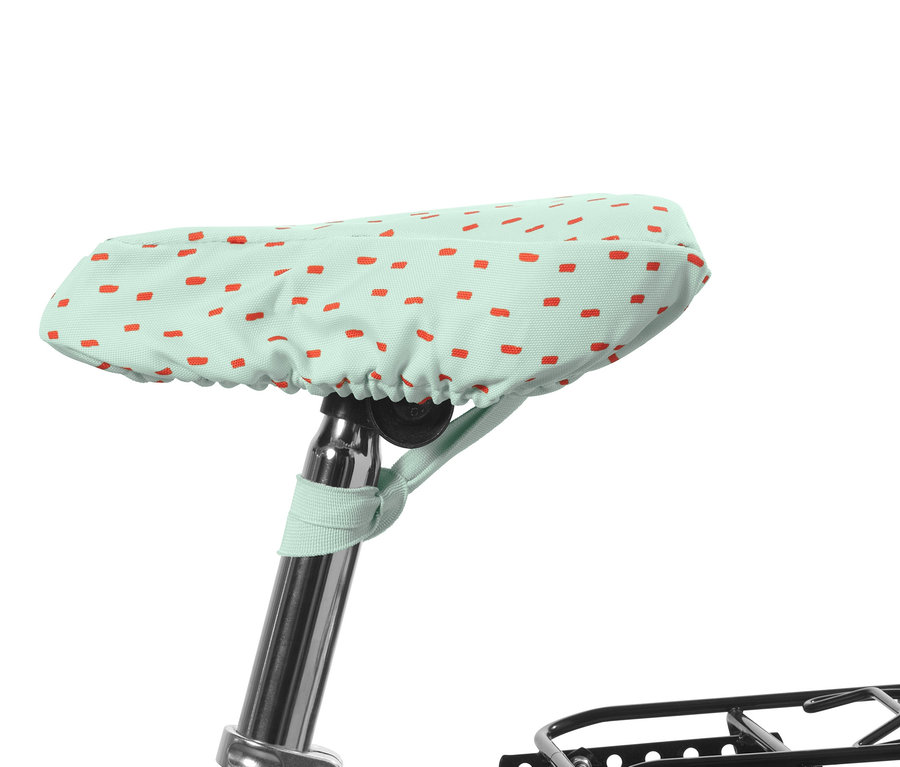 Ein mintgrüner Fahrrad-Sattelbezug für Kinder mit roten Rechtecken.