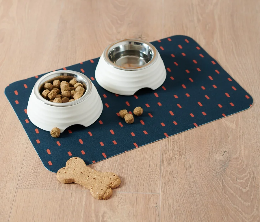 Zwei Näpfe stehen auf einer Napfunterlage aus Vlies auf dem Boden.