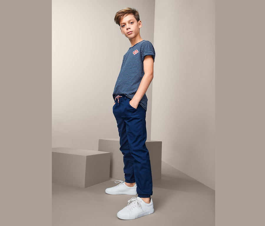 Junge mit gestreiftem T-Shirt und blauer Schlupfhose.