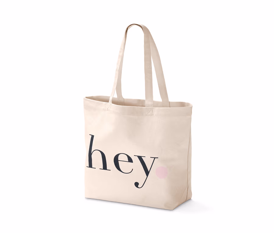 Ein Canvas-Shopper mit dem schwarzen Schriftzug hey und einem pinken Punkt.
