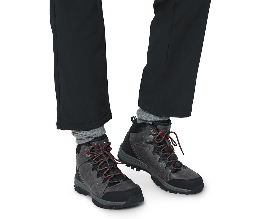 Beine in schwarzen Hosen und Trekkingschuhen.