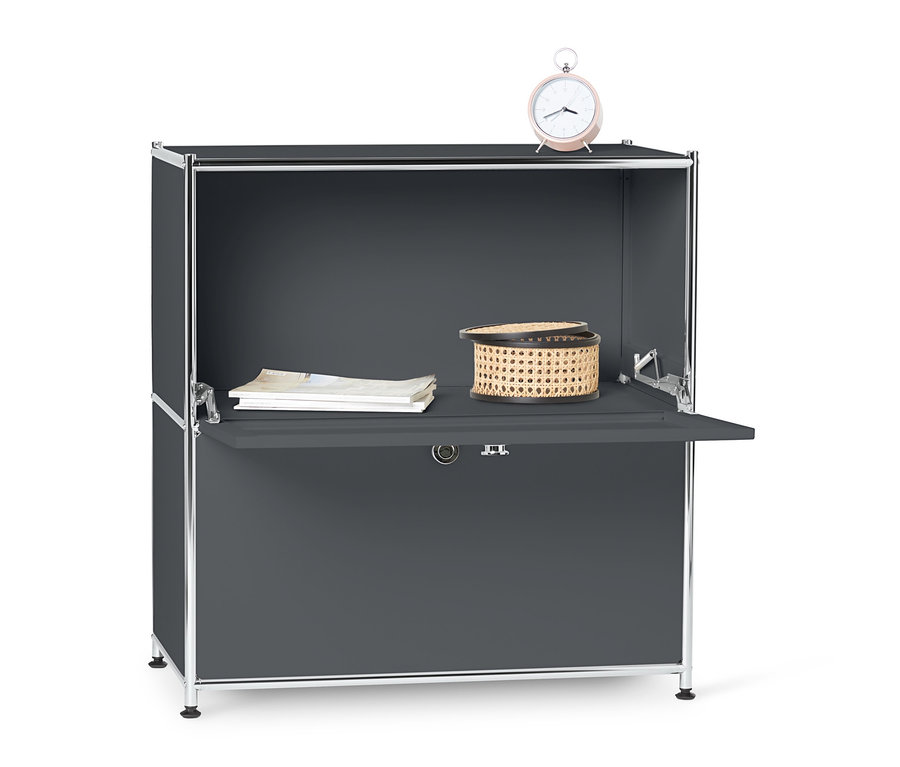 Graues Sideboard Metall »CN3« mit Klappenfächern, auf dem ein Weidenkorb, Dokumente und ein rosa Wecker stehen.