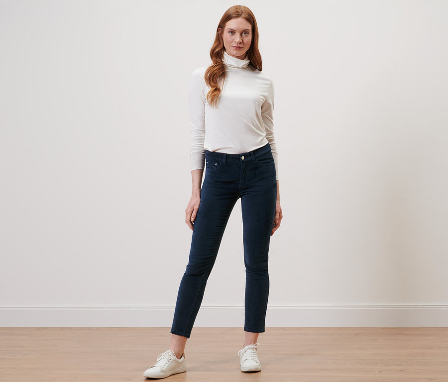 Rothaarige Frau posiert in dunkelblauer Samthose.