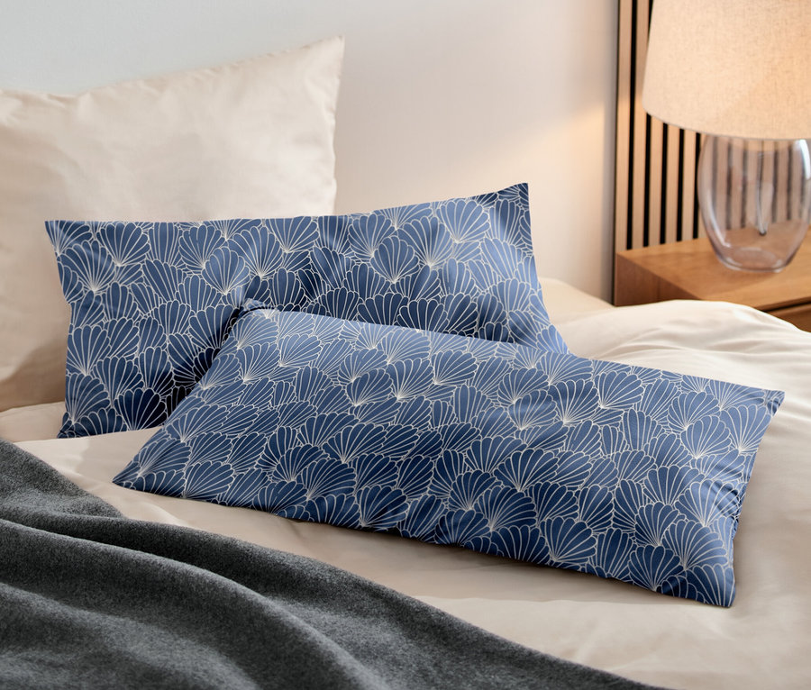 Zwei blaue Microfaser-Kopfkissenbezüge mit Muster liegen auf einem Bett. Die Maße der Bezüge sind ca. 80 x 40 cm.