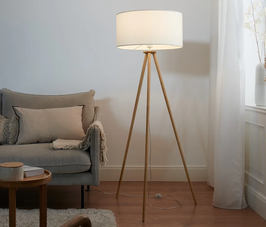 Wohnzimmer mit Sofa und Dreibein Stehleuchte aus Holz.