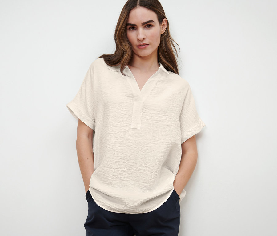 Frau posiert in einer kurzärmeligen Bluse.