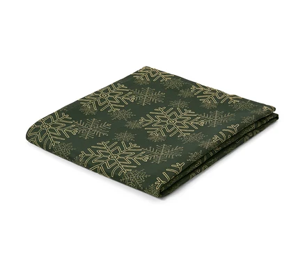 Eine grüne Jacquard-Tischdecke mit Schneeflockenmuster, gefaltet auf einem weißen Hintergrund.