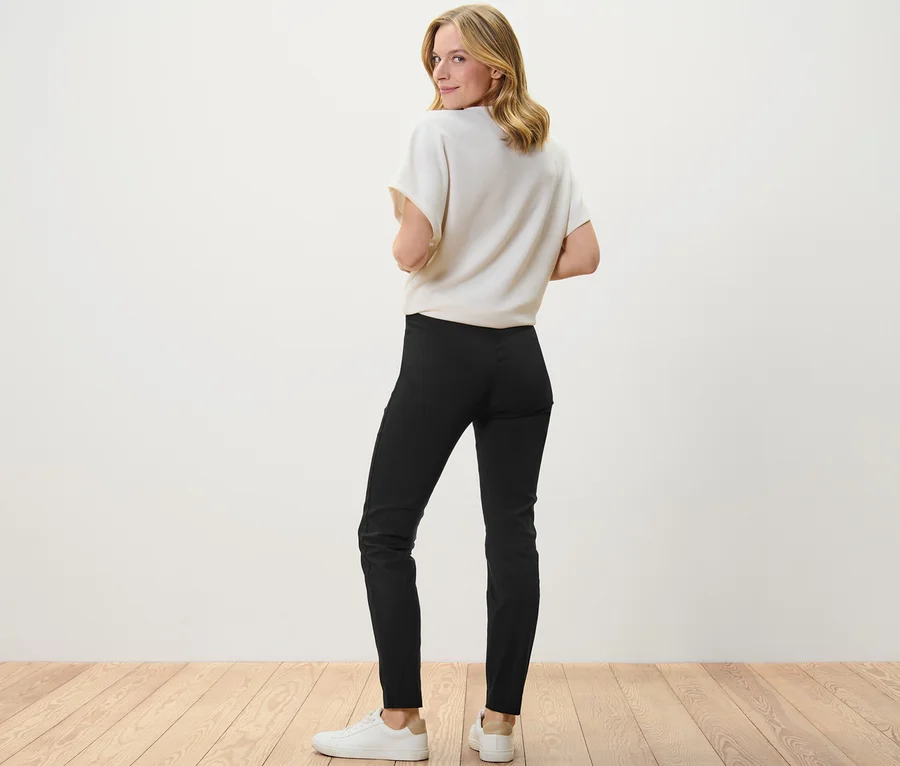 Frau blickt über die Schulter und trägt eine schwarze Stretchhose.