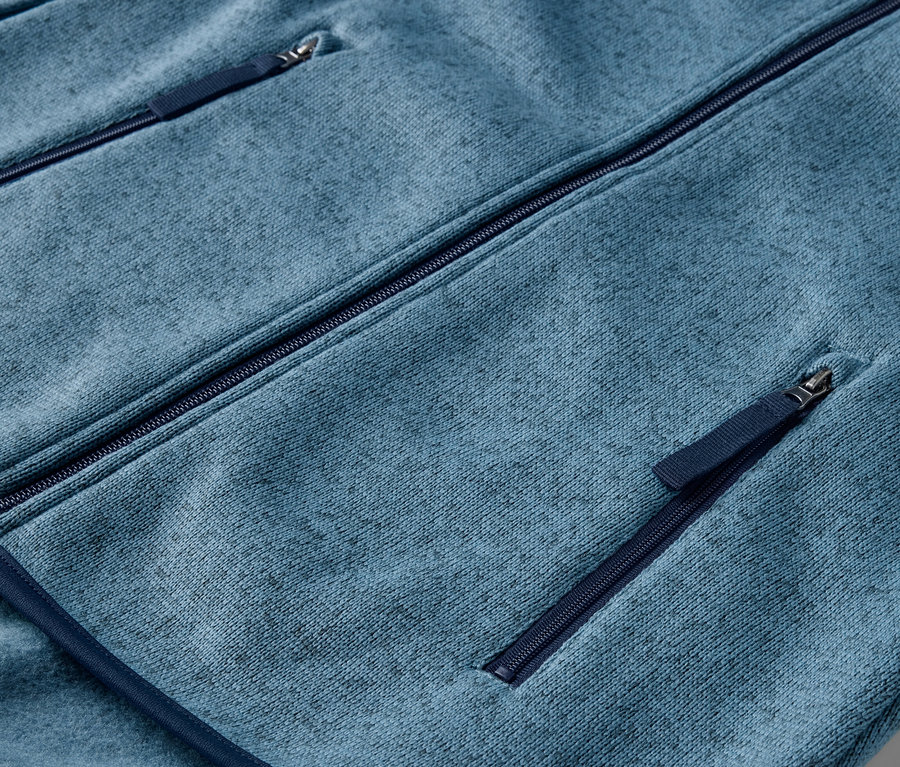 Detailansicht einer dunkelblauen Strickfleece-Jacke mit Reißverschlusstaschen.