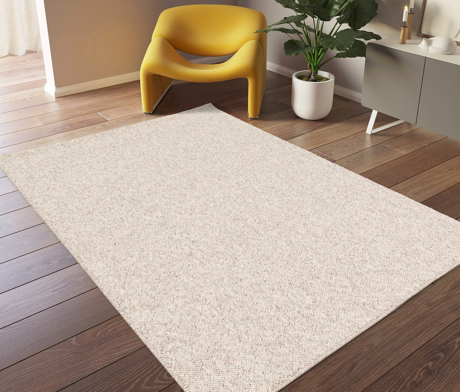 Ein »Lino« Teppich in Greige liegt auf einem Holzboden. Im Hintergrund stehen ein gelber Sessel und ein grauer Schrank.