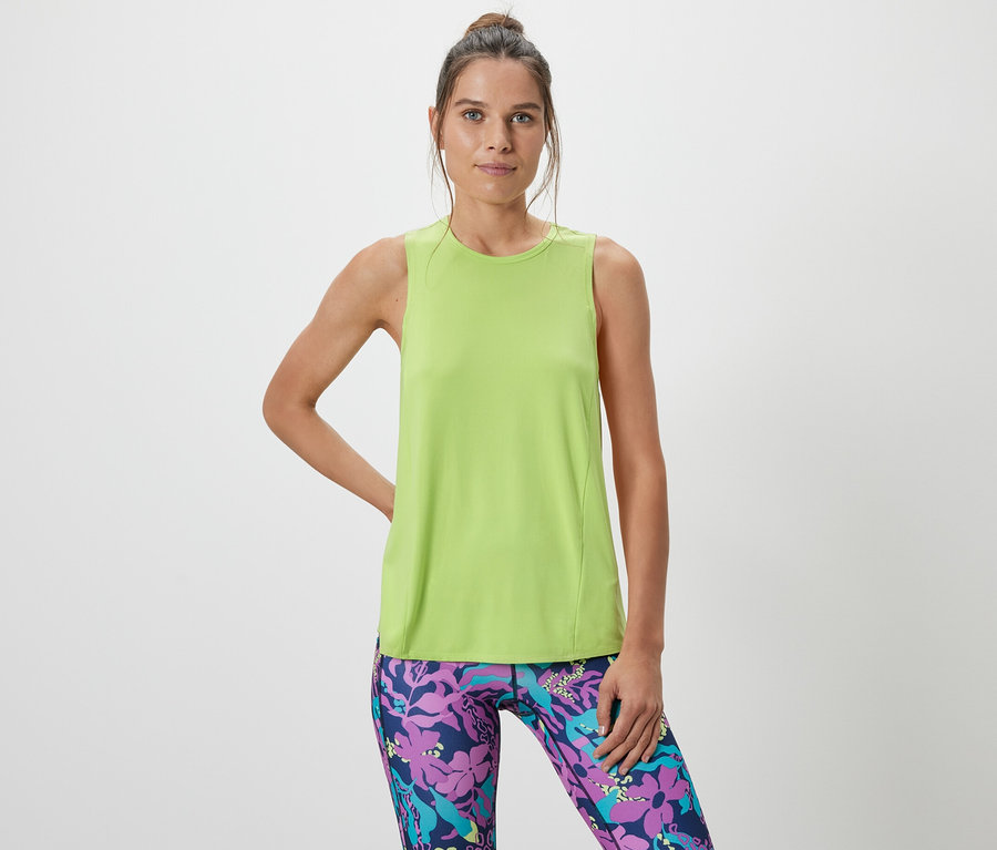Frau posiert in einem limefarbenen Sport-Top aus einem zweiteiligen Set und gemusterten Leggings.