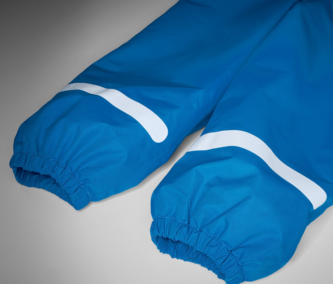 Detailaufnahme einer blauen Kinder-Thermo-Regenhose mit weißen Reflexstreifen.