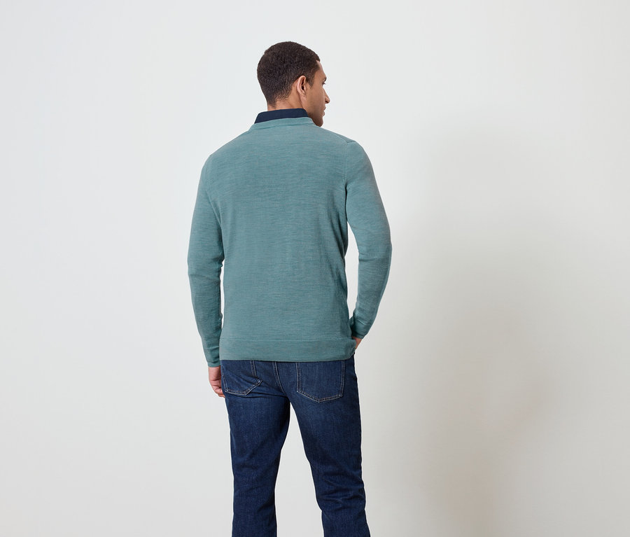 Mann von hinten trägt einen blaugrünen Pullover und Jeans.