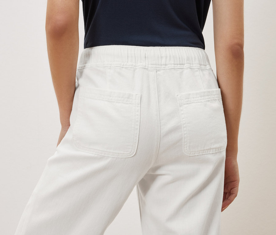 Rückansicht einer Frau in weißen Hosen.