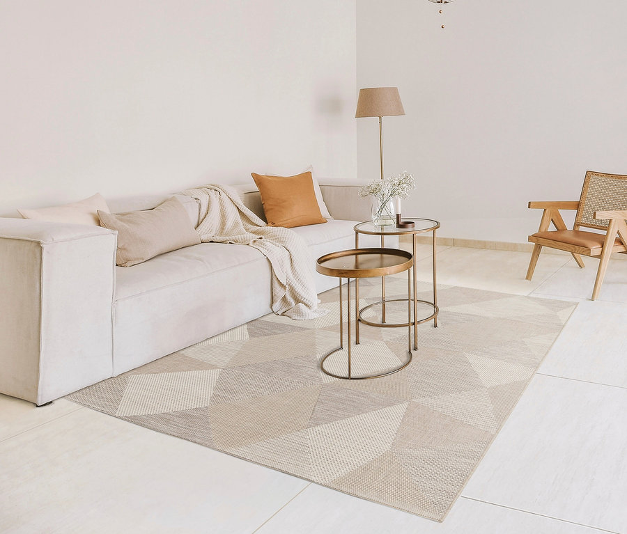 Wohnzimmer mit beigem Sofa, Beistelltischen und Outdoor-Teppich »Sandstone Shapes«.
