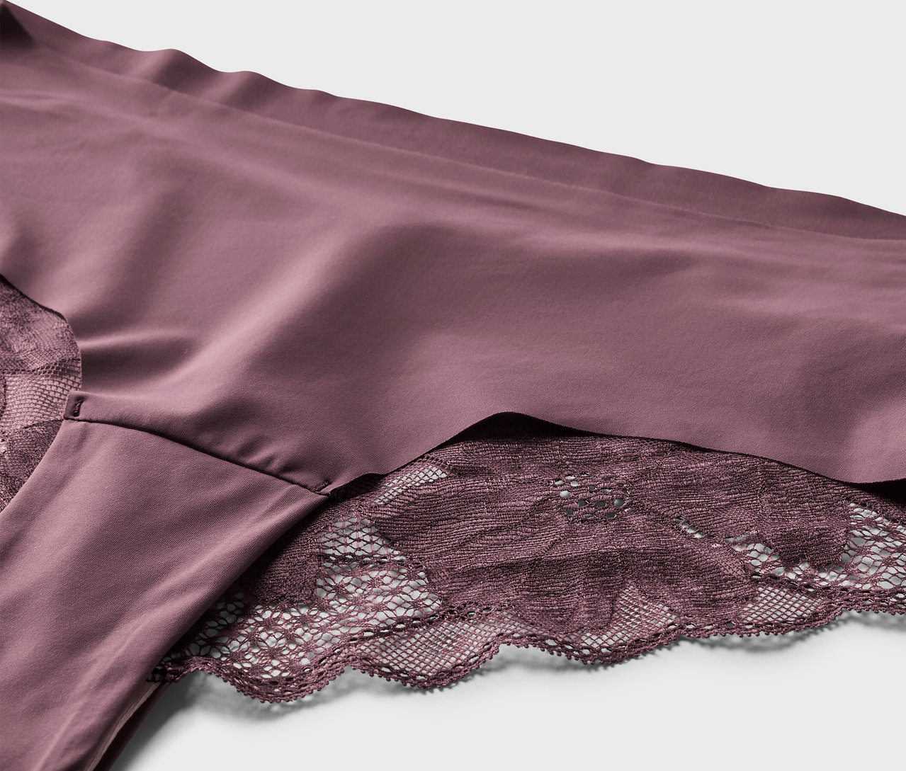 Nahaufnahme von 2 Magic-Cut-Brazil-Slips in Aubergine mit Spitze.