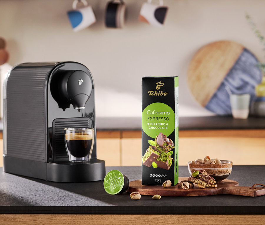 Kaffeemaschine gießt Kaffee in eine Tasse neben Packung Cafissimo Flavoured Espresso - Pistachio & Chocolate.