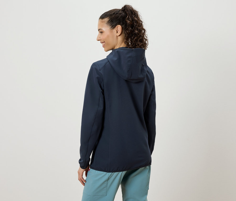 Frau von hinten, trägt eine dunkelblaue Kapuzenjacke und hellblaue Hosen.