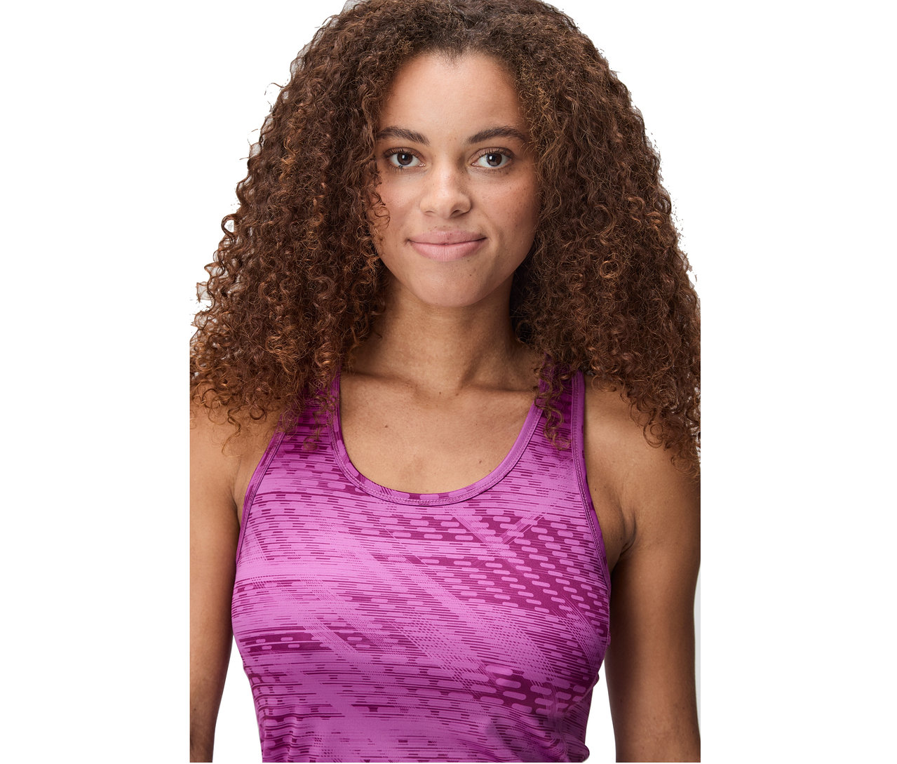 Frau mit lockigem braunem Haar, die ein ärmelloses, gemustertes, pinkfarbenes Oberteil trägt.