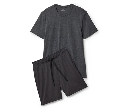 Graues T-Shirt liegt neben Shorts mit Kordelzug auf weißem Grund.