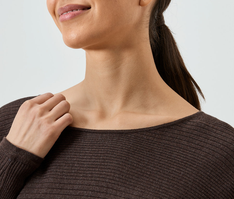 Nahaufnahme einer Frau mit einem braunen, gerippten Langarmshirt.
