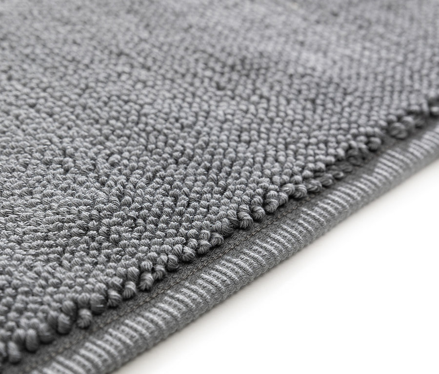 Nahaufnahme einer grauen Badematte mit Noppenstruktur.