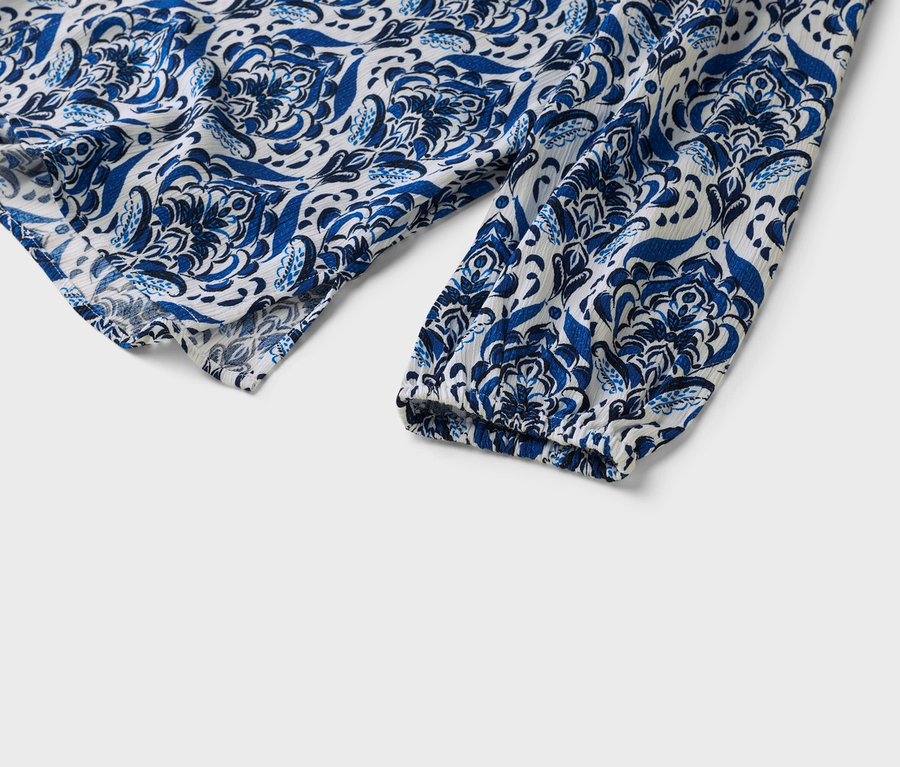 Nahaufnahme eines weiß-blau gemusterten Blusenärmels.