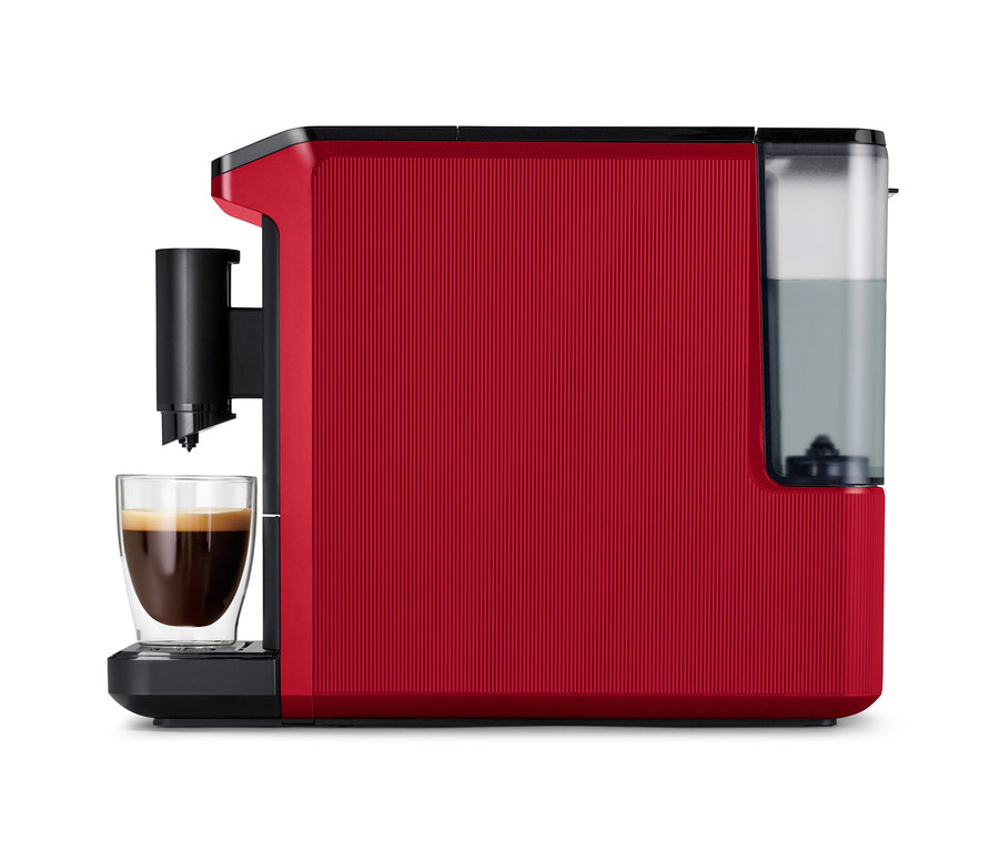 Rote Kaffeemaschine mit strukturierter Seitenwand, die Kaffee in ein doppelwandiges Glas ausgibt, mit einem transparenten Wassertank rechts.