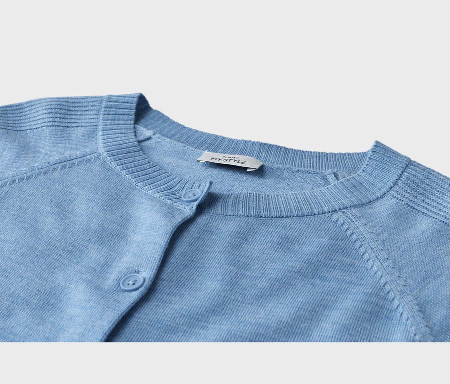 Nahaufnahme einer hellblauen Strickjacke mit geripptem Halsausschnitt und drei sichtbaren hellblauen Knöpfen. Ein weißes Etikett mit „MY STYLE“ ist innen am Kragen zu sehen.