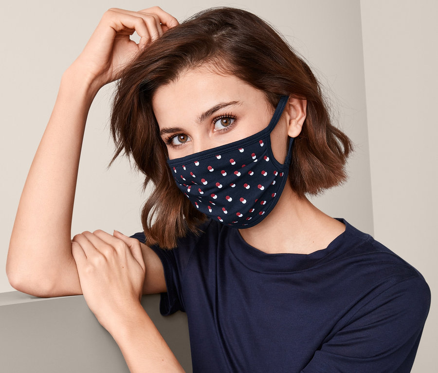 Frau trägt eine marineblaue 3 Community-Masken mit roten und weißen Punkten.