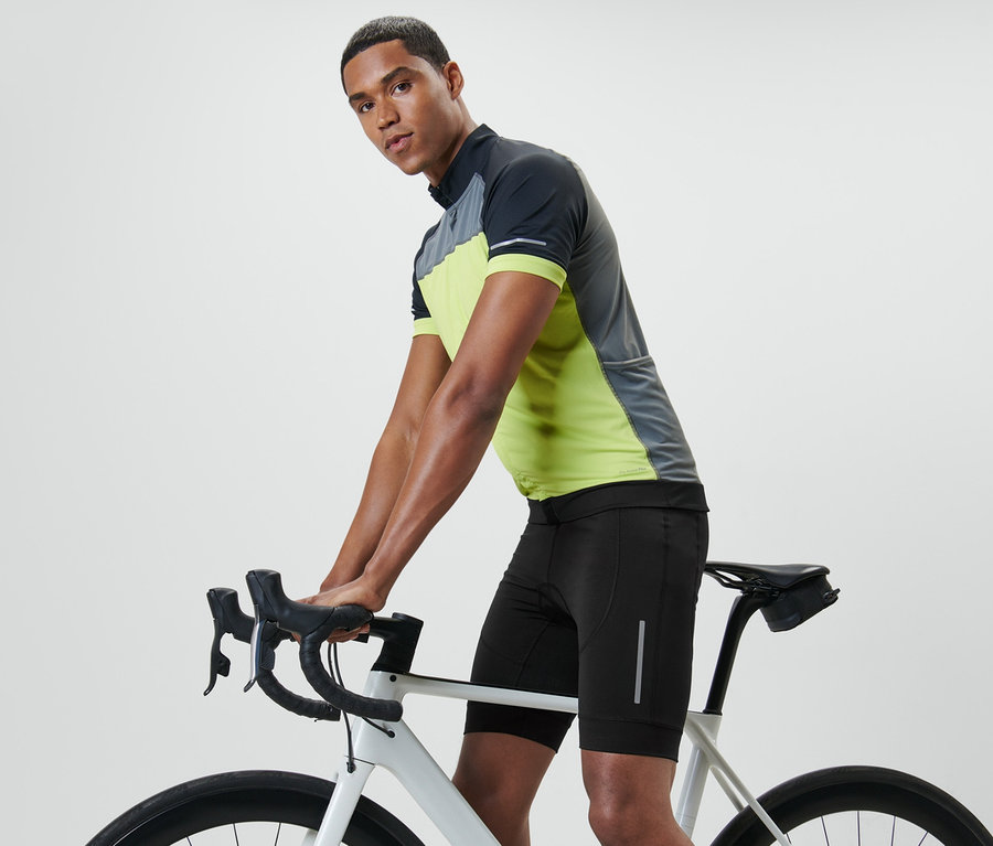 Mann, der sich auf den Lenker eines Fahrrads stützt, trägt eine Fahrradhose.