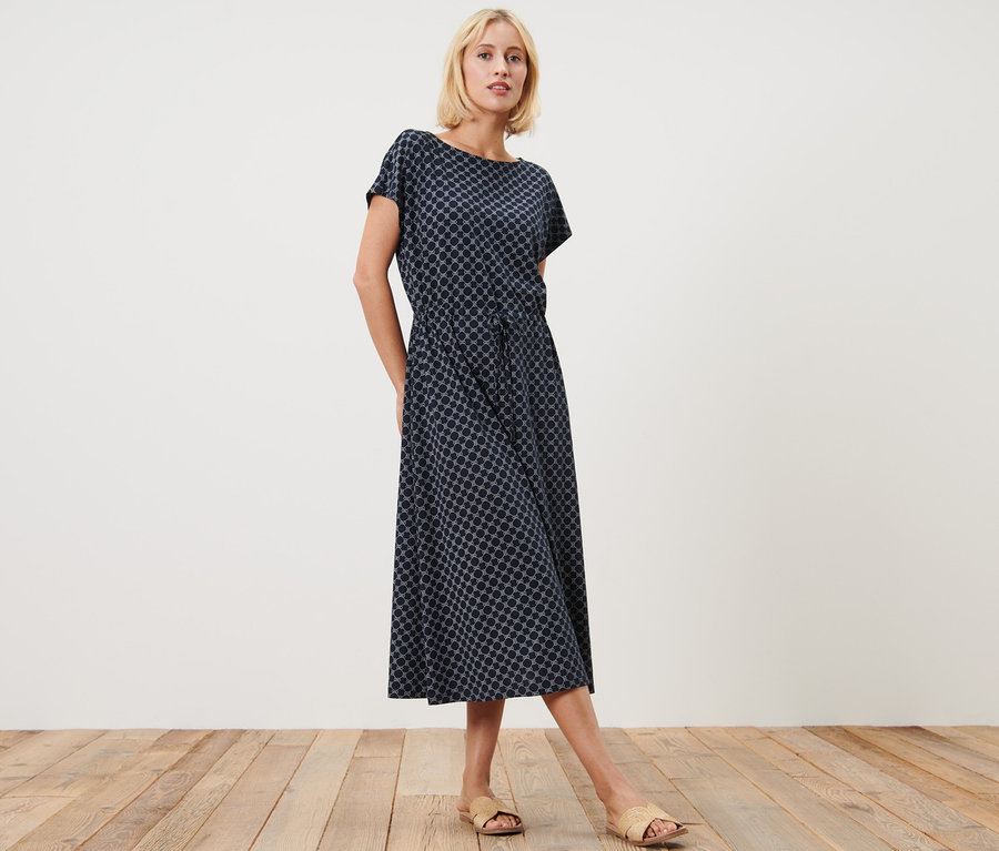 Blonde Frau posiert in einem bedruckten Jerseykleid.